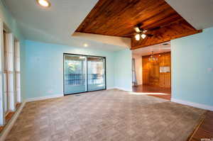 Unfurnished living room featuring recessed lighting, wooden ceiling, a raised ceiling, light carpet, and ceiling fan