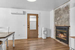 Foyer entrance featuring a tile fireplace, wood finished floors, a textured ceiling, and a wall mounted air conditioner