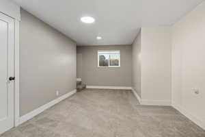 Unfurnished room featuring light colored carpet and stairway