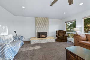 Living room with carpet, a brick fireplace, recessed lighting, and ceiling fan