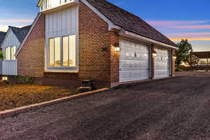Property exterior at dusk with board and batten siding, brick siding, and a garage