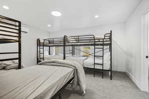 Bedroom featuring recessed lighting, light carpet, and an AC wall unit