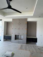 Unfurnished living room featuring a raised ceiling and ceiling fan