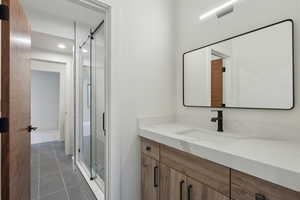 Full bathroom with vanity, light tile patterned flooring, and a shower stall