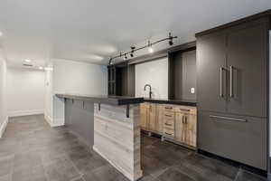 Kitchen with a kitchen breakfast bar, a peninsula, light brown cabinets, dark tile patterned flooring, and modern cabinets