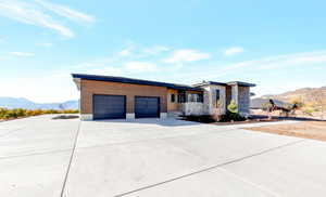 Contemporary home featuring a mountain view, stone siding, concrete driveway, and an attached garage