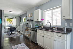 Kitchen featuring dark stone countertops, healthy amount of natural light, appliances with stainless steel finishes, and white cabinetry
