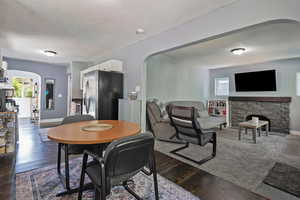 Dining area with arched walkways, dark wood finished floors, a textured ceiling, and a fireplace