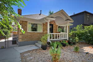 View of front of house featuring a gate, brick siding, a chimney, and a shingled roof