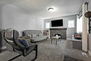 Living room with carpet flooring, a fireplace, and a textured ceiling