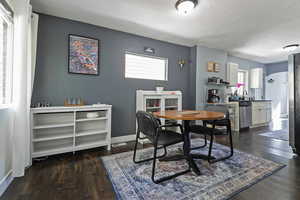 Dining area with dark wood-style flooring and a textured ceiling