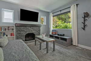 Living room with carpet flooring and a stone fireplace