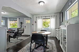 Dining space with arched walkways, dark wood-style floors, and a textured ceiling