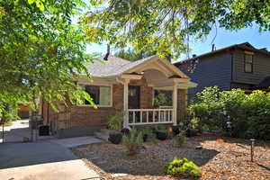 View of front of house featuring a gate, brick siding, and a shingled roof