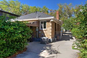 View of property exterior featuring brick siding, a chimney, and roof with shingles