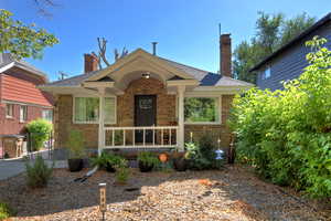 View of front of property with a chimney, brick siding, a shingled roof, and a porch