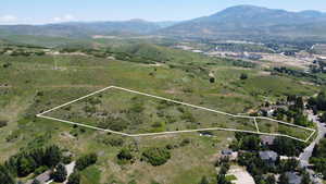 Aerial view of property and surrounding area featuring a mountainous background and property boundaries highlighted