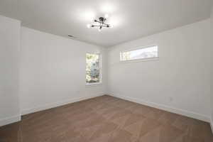 Carpeted spare room featuring baseboards and a chandelier
