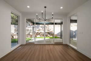 Unfurnished dining area featuring wood finished floors, plenty of natural light, a chandelier, and recessed lighting