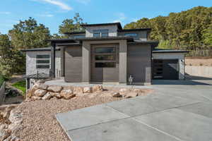 View of front of house with stone siding, driveway, and a garage