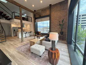Living room,  featuring a high ceiling, stairway, and recessed lighting and exposed brick.