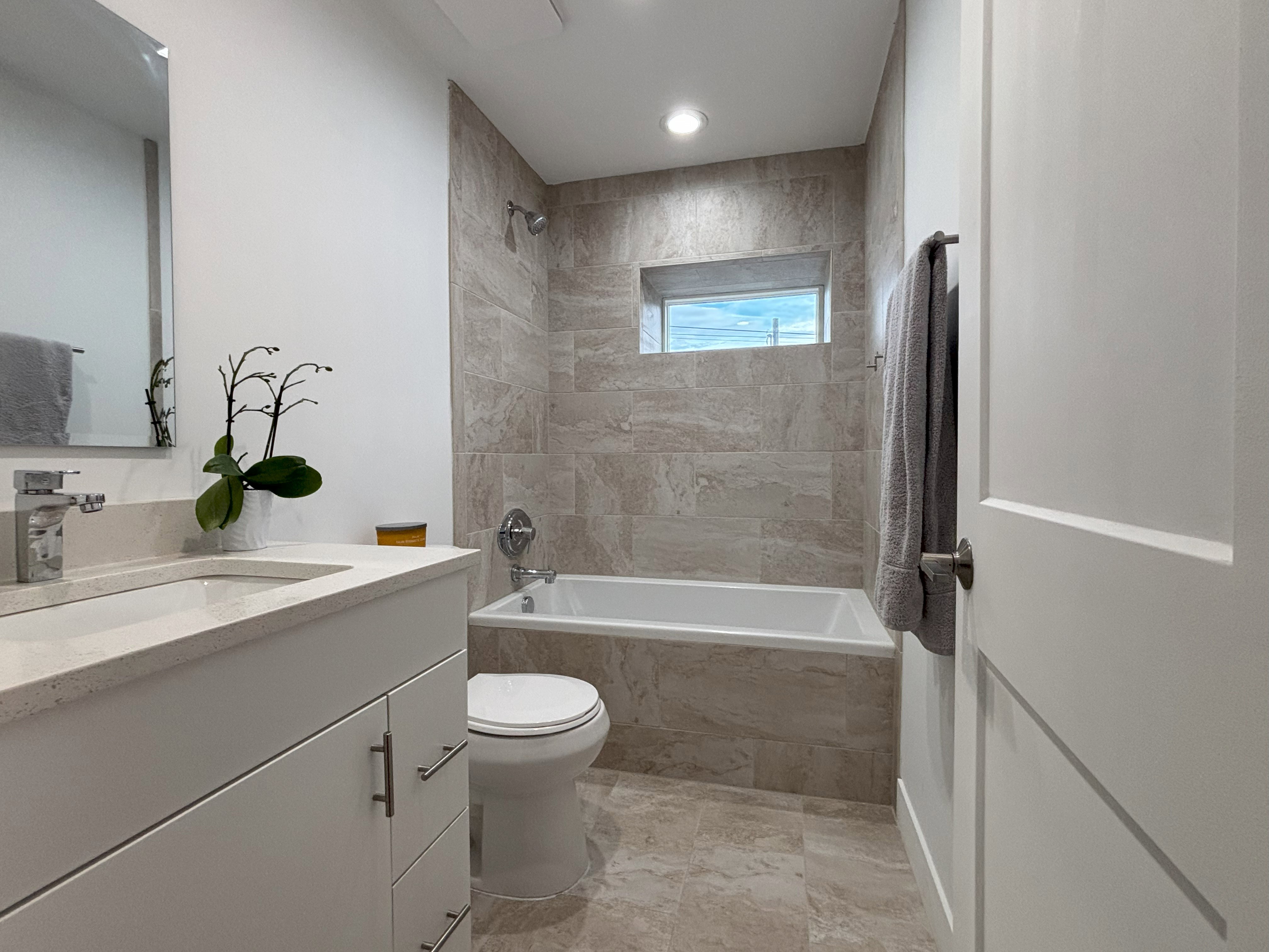 Bathroom with tiled shower / bath combo and vanity