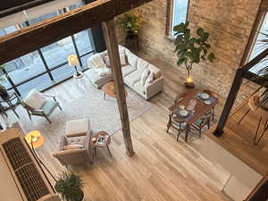 Living room featuring wood finished floors, brick wall, and a towering ceiling