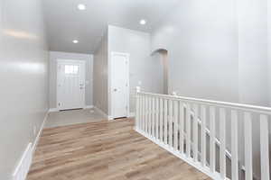 Entrance foyer with light wood-style flooring, recessed lighting, and arched walkways