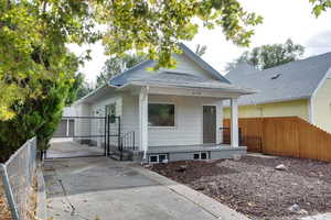 View of front of house with a gate, covered porch, and roof with shingles