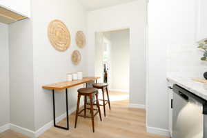 Kitchen with white cabinetry, dishwasher, and light stone countertops