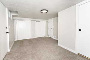 Unfurnished bedroom with a textured ceiling, two closets, and carpet flooring