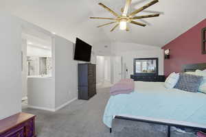 Bedroom with vaulted ceiling, light carpet, ceiling fan, and ensuite bath