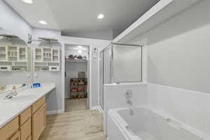 Bathroom featuring vanity, a stall shower, a bath, light wood-type flooring, and a spacious closet
