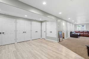 Basement with recessed lighting, light carpet, and light wood-type flooring