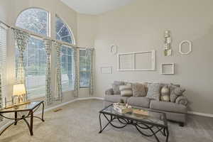 Living room with carpet flooring and a towering ceiling