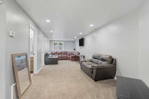 Living area with light colored carpet and recessed lighting