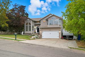 View of front of home with driveway, a garage, a front yard, and roof with shingles