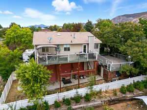 Rear view of house featuring a patio, a fenced backyard, a deck with mountain view, a shingled roof, and view of scattered trees