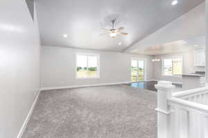 Spare room featuring carpet flooring, lofted ceiling, a ceiling fan, a chandelier, and recessed lighting