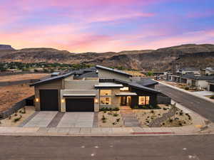 Contemporary home featuring stucco siding, a garage, driveway, stone siding, and a mountain view