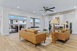 Living room featuring wood tiled floors, recessed lighting, a multi sided fireplace, and a ceiling fan