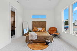 Carpeted bedroom with ensuite bath and recessed lighting