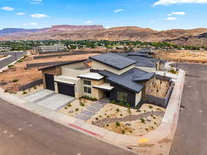 Modern home with stucco siding, stone siding, concrete driveway, a mountain view, and a garage