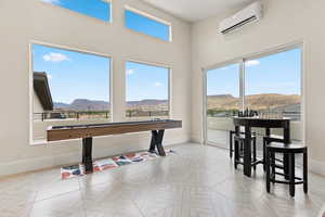 Rec room featuring a mountain view, an AC wall unit, and a high ceiling