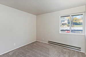 Spare room with a baseboard radiator, carpet, and a textured ceiling