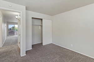 Unfurnished bedroom featuring carpet flooring, a textured ceiling, and a closet