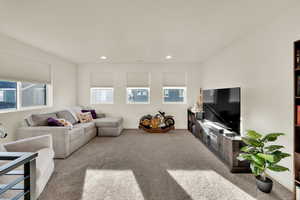 Living area with light carpet and recessed lighting