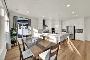 Dining room with light wood finished floors and recessed lighting