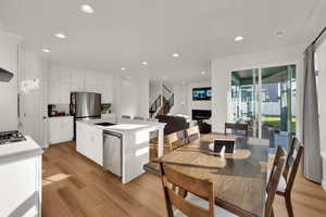 Kitchen with a center island with sink, white cabinets, light wood-style floors, recessed lighting, and appliances with stainless steel finishes