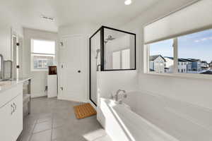 Primary en-suite bathroom with vanity, a shower stall, a bath, light tile patterned floors, and recessed lighting